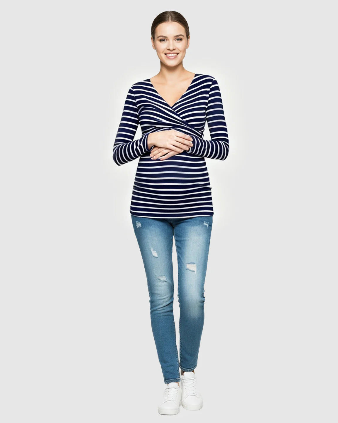 Smiling pregnant woman in a navy and white striped long-sleeve V-neck wrap maternity and nursing shirt.