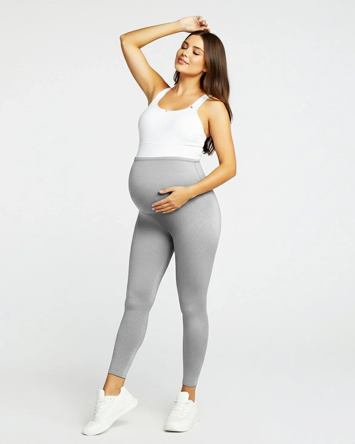 Smiling pregnant woman in light gray sculpting ankle-length maternity leggings with an over-the-bump waistband.