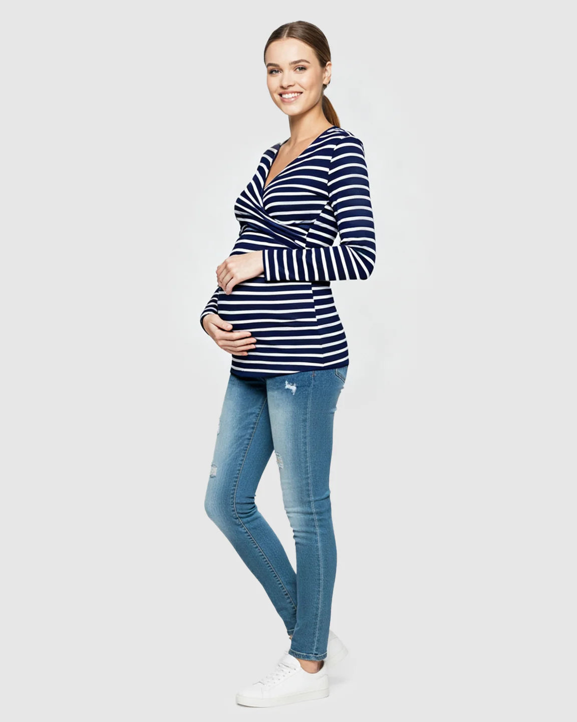 Smiling pregnant woman in a navy and white striped long-sleeve V-neck wrap maternity and nursing shirt.