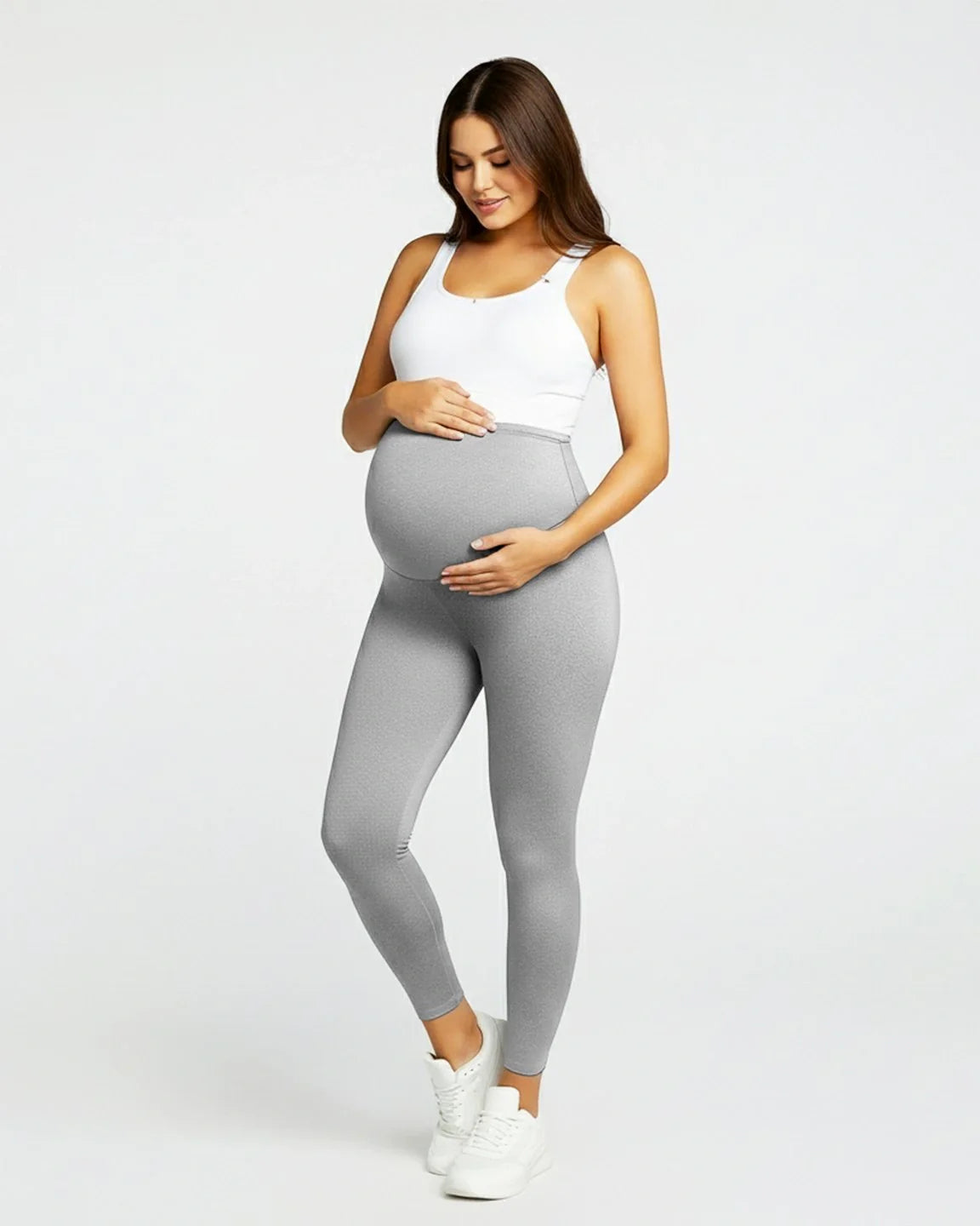Smiling pregnant woman in light gray sculpting ankle-length maternity leggings with an over-the-bump waistband.