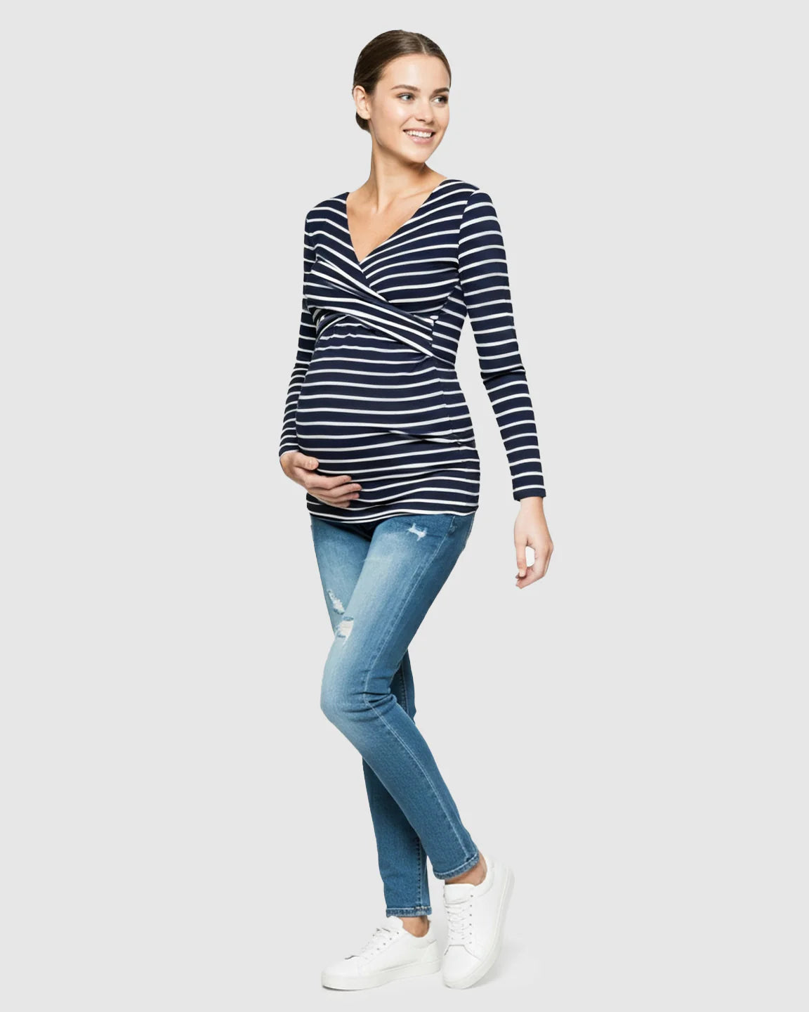 Smiling pregnant woman in a navy and white striped long-sleeve V-neck wrap maternity and nursing top.