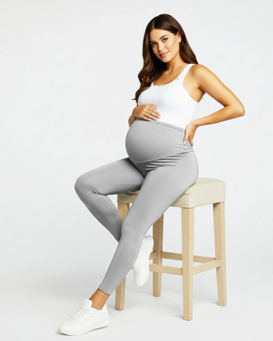 Pregnant woman in light gray sculpting ankle-length maternity leggings with a subtle dotted pattern.