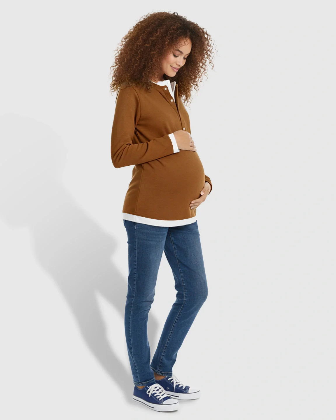 Pregnant woman in a brown button-front henley maternity and nursing top with white trim, blue jeans, and sneakers.