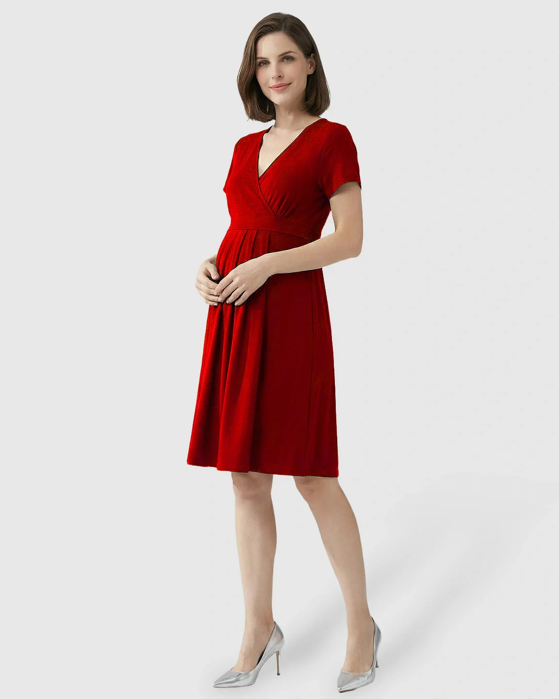 Woman in a red V-neck A-line maternity and nursing dress with short sleeves, posing in silver heels.