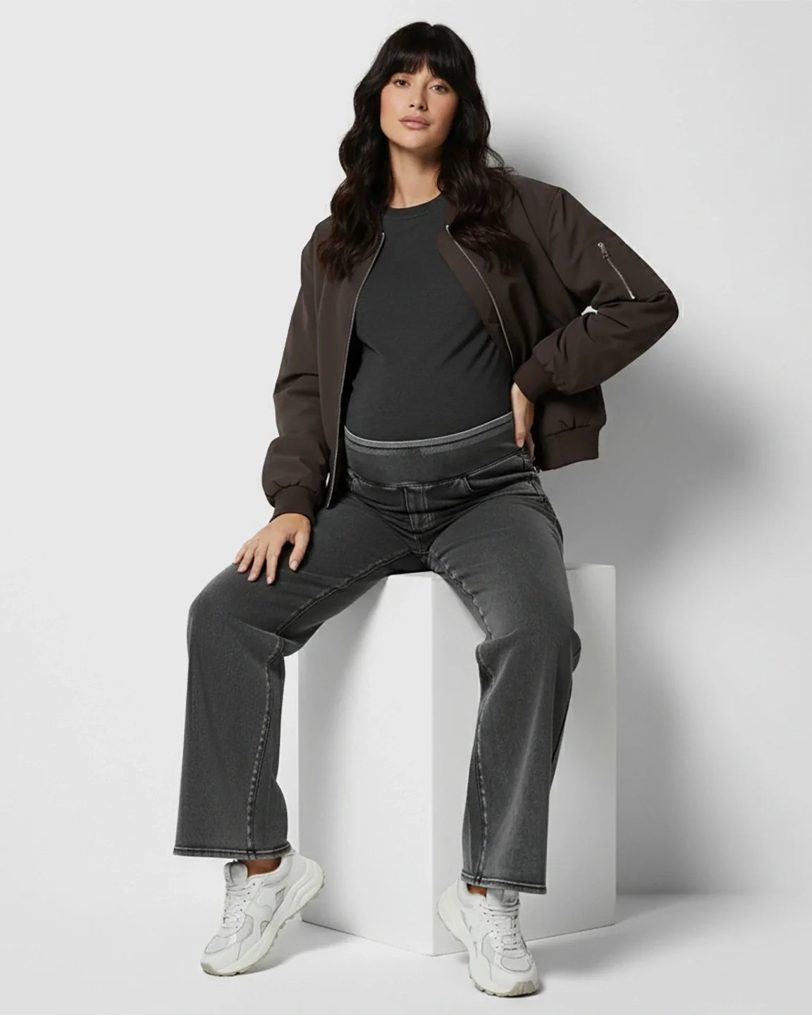 Pregnant woman wearing high-waist, wide-leg charcoal maternity denim jeans with a soft belly band.