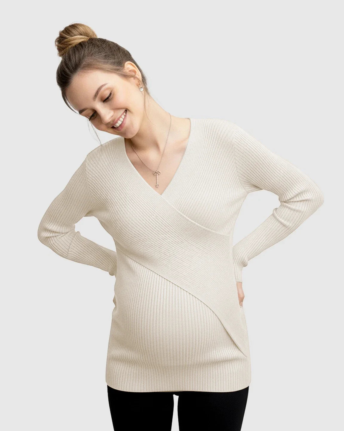 Smiling pregnant woman in a cream faux-wrap ribbed maternity top with a V-neck.
