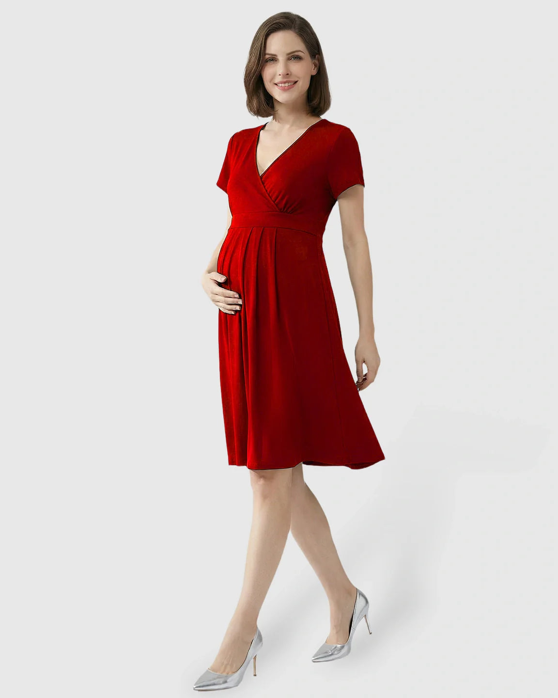 Smiling pregnant woman in a red V-neck A-line maternity and nursing dress with short sleeves.