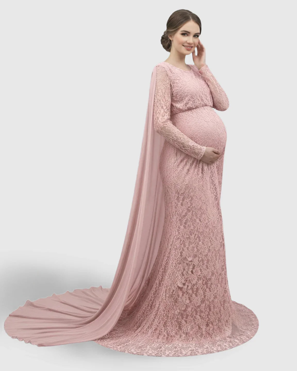 Smiling pregnant woman in a pink lace maternity gown with long sleeves, empire waist, and trailing chiffon cape.