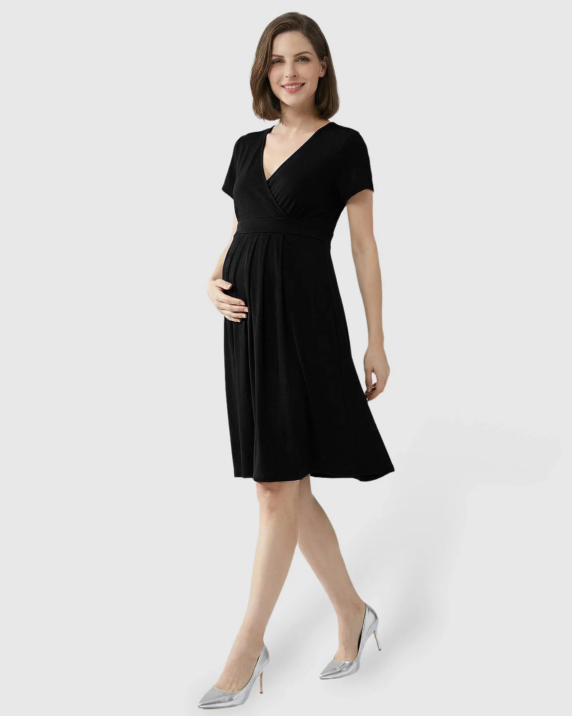 Smiling pregnant woman in a black V-neck A-line maternity and nursing dress with hidden nursing openings.