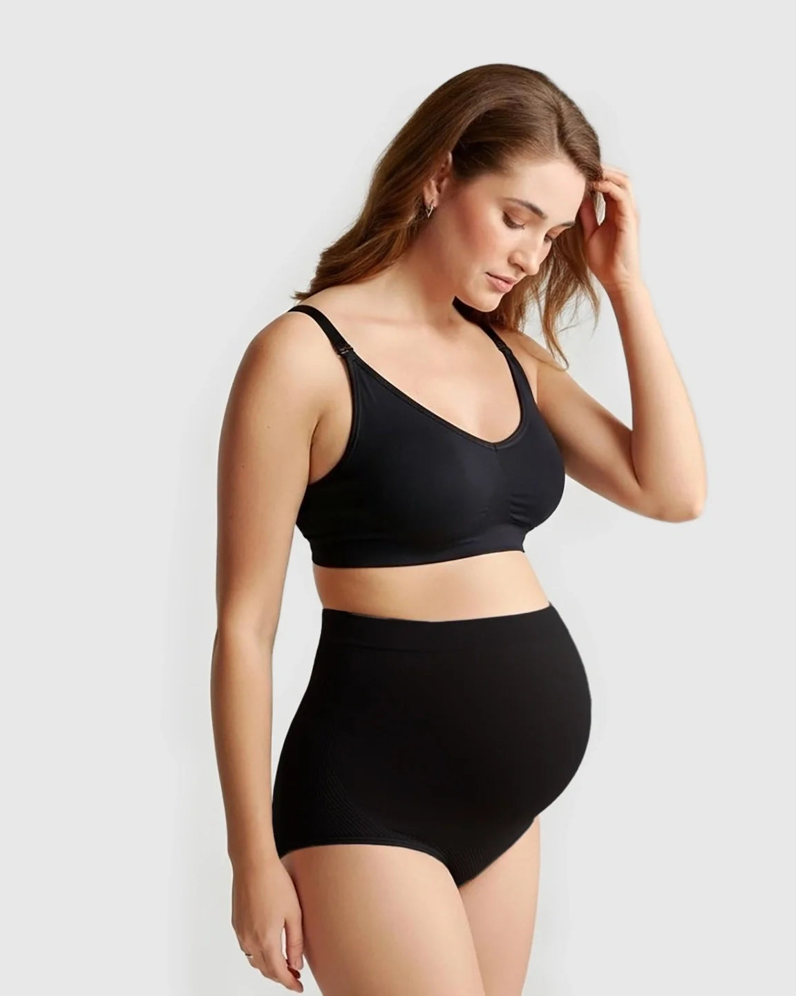 Pregnant woman wearing black seamless high-waist maternity panties and a matching bra.
