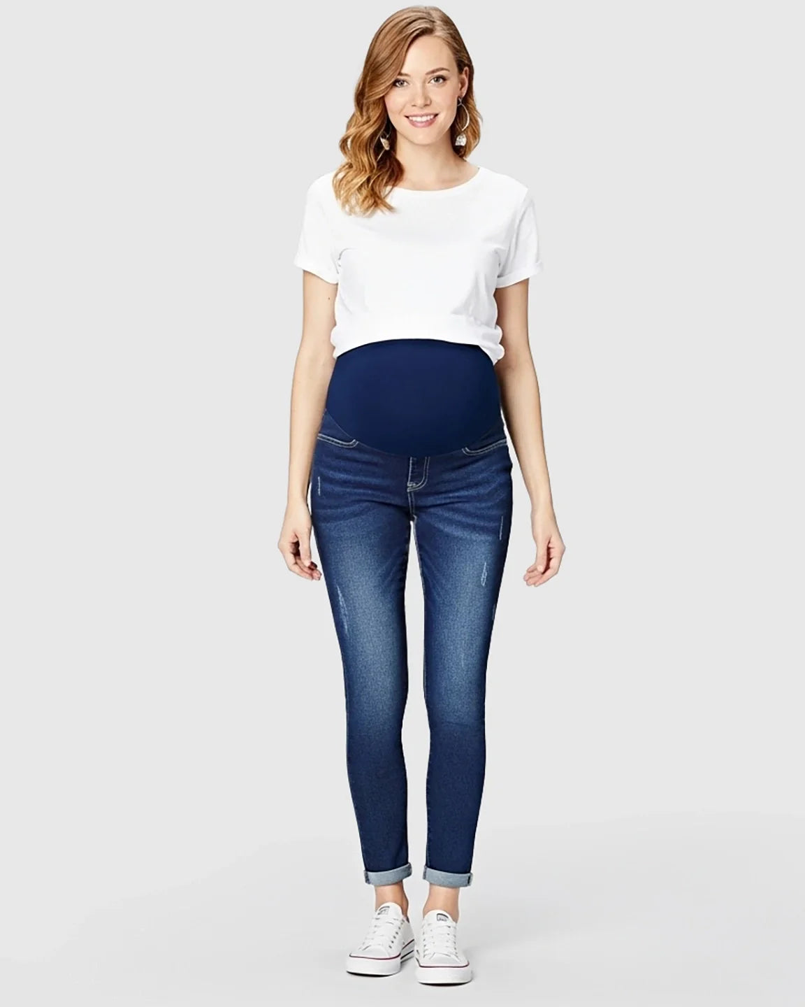 Smiling pregnant woman wearing dark wash distressed maternity skinny jeans with a full panel.