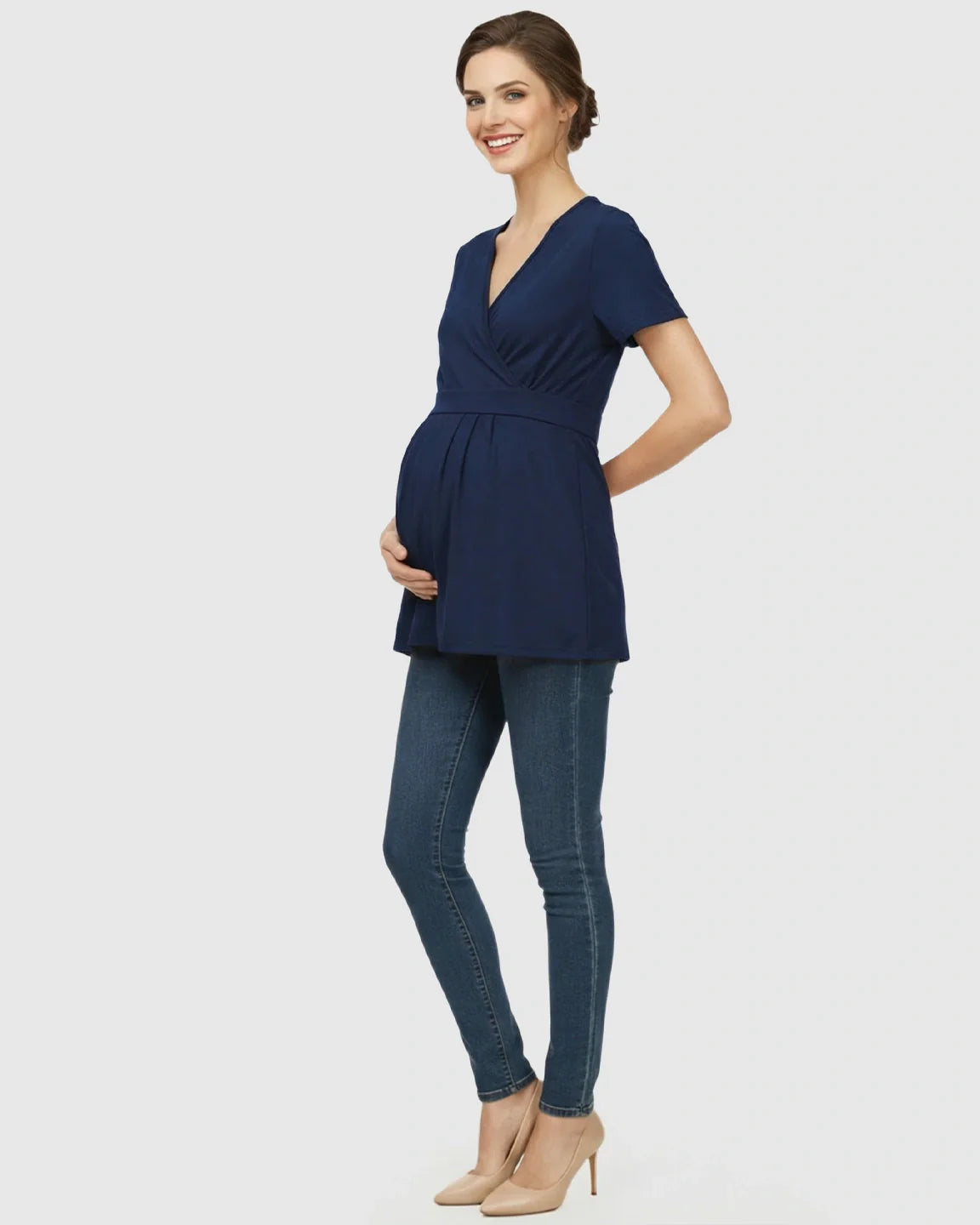 Smiling pregnant woman in a navy V-neck wrap-style maternity top with an adjustable waist tie.