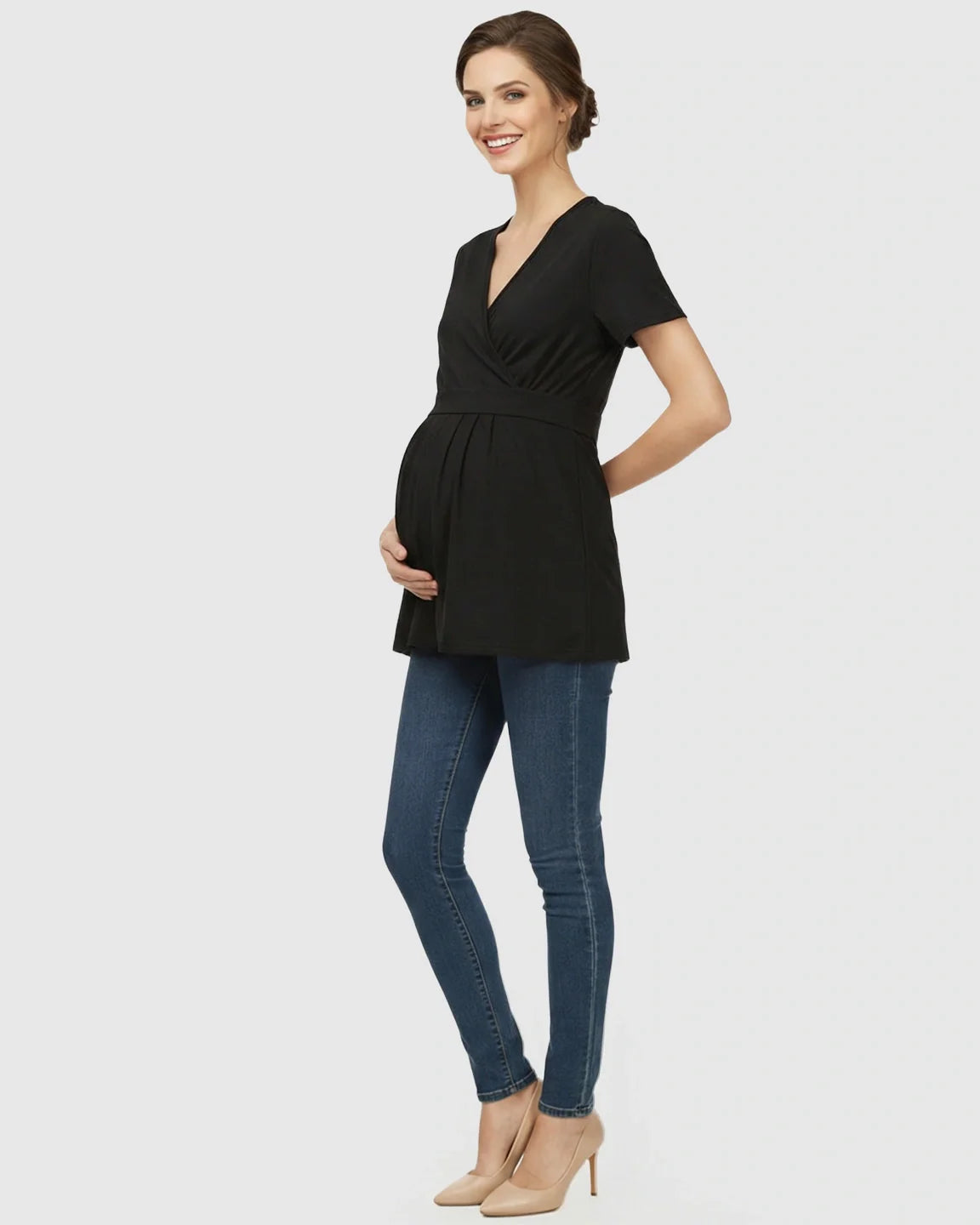 Smiling pregnant woman in a black V-neck wrap-style maternity top with adjustable waist tie and blue jeans.