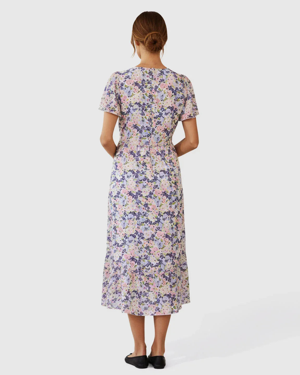 Back view of a floral V-neck wrap-style maternity midi dress with flutter sleeves and an adjustable tie waist.
