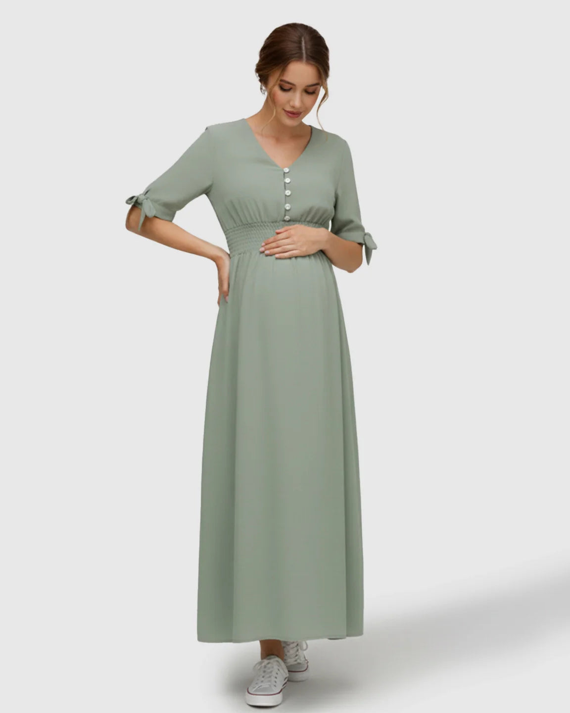Pregnant woman in a mint green V-neck empire waist maternity maxi dress with button details and tied sleeves.