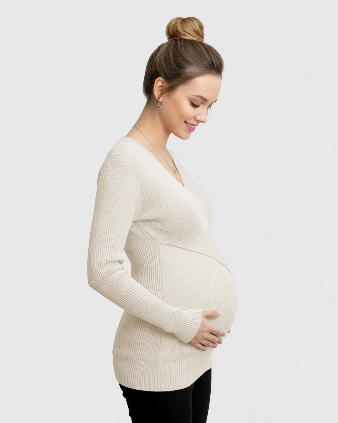 Smiling pregnant woman in a cream faux-wrap ribbed maternity top, flattering her bump.