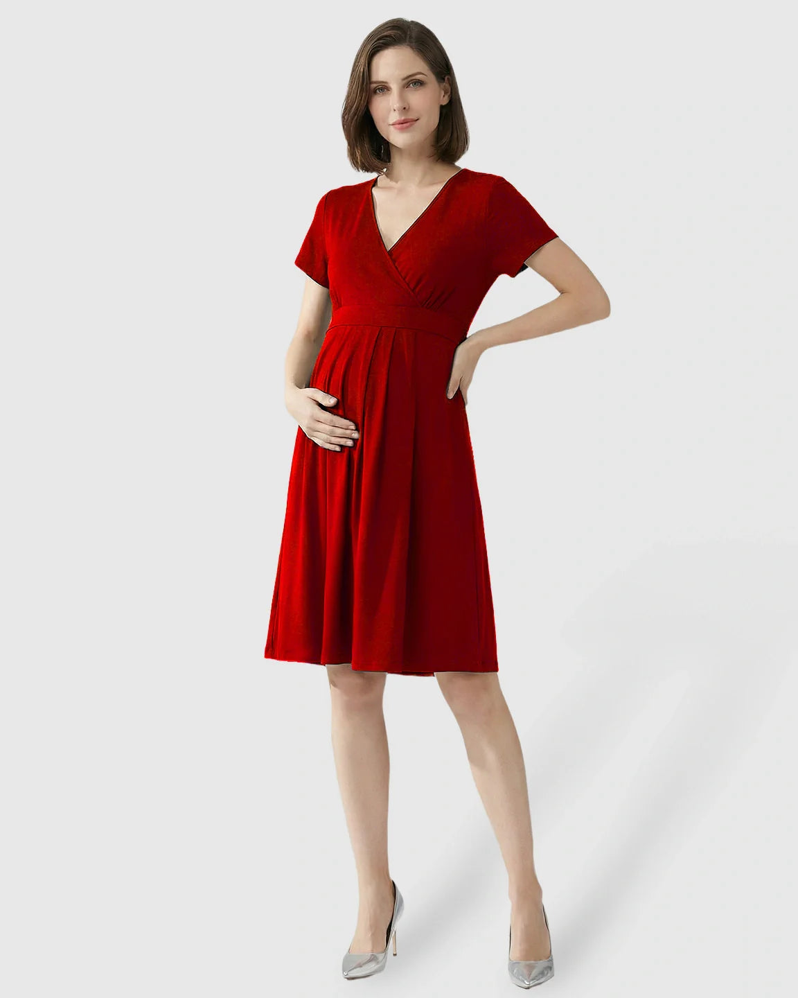 Woman in a red V-neck A-line maternity and nursing dress, short sleeves, holding her baby bump.