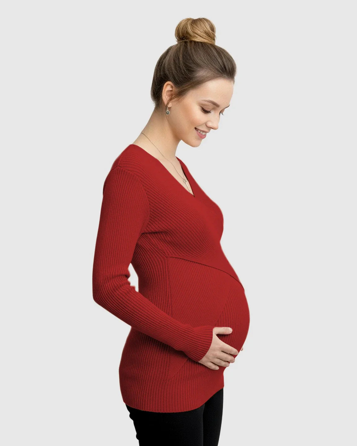 Smiling pregnant woman in a red faux-wrap ribbed maternity top with long sleeves, holding her belly.