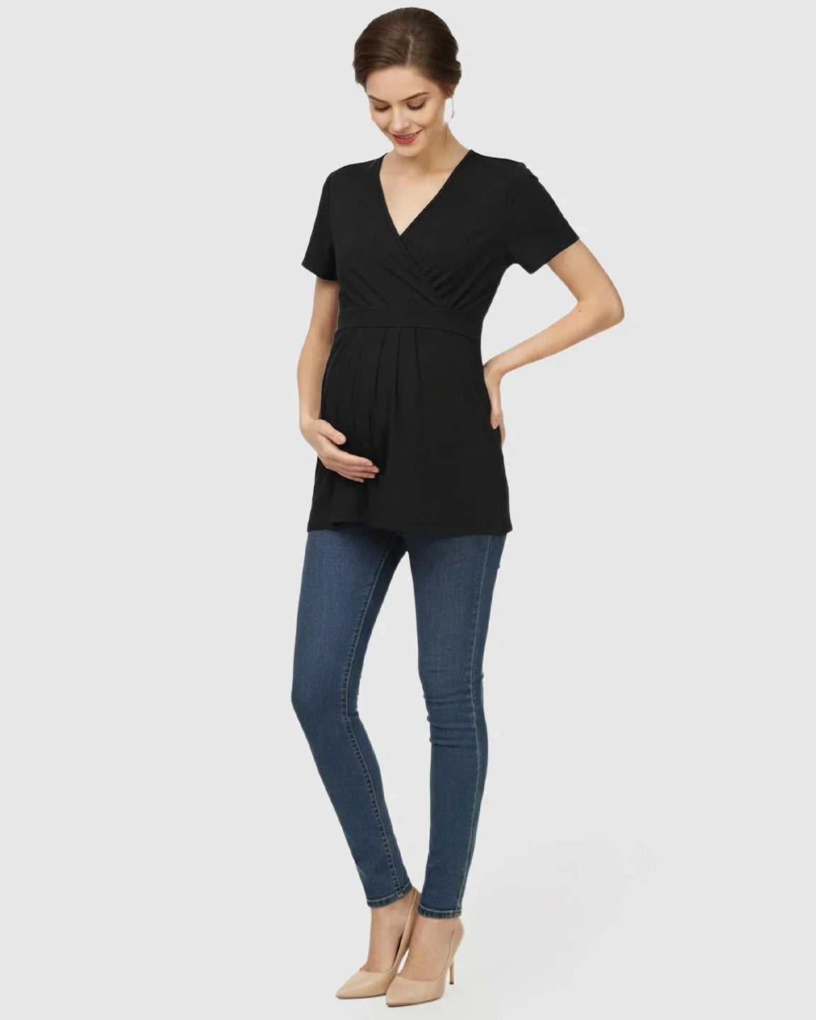 Smiling pregnant woman in a black V-neck wrap-style maternity top with an adjustable waist tie.