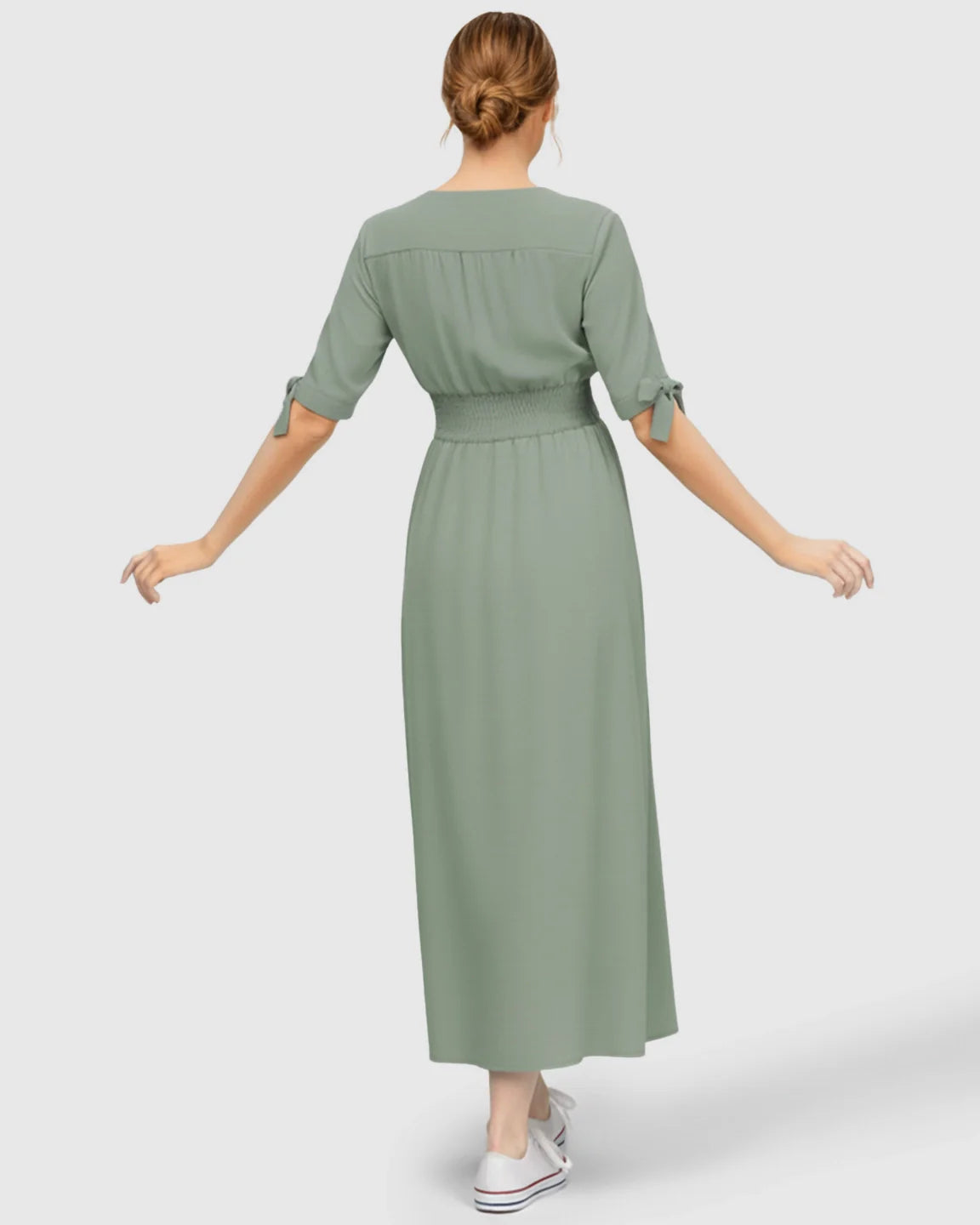 Back view of a woman in a mint green V-neck empire waist maternity maxi dress with tied short sleeves.