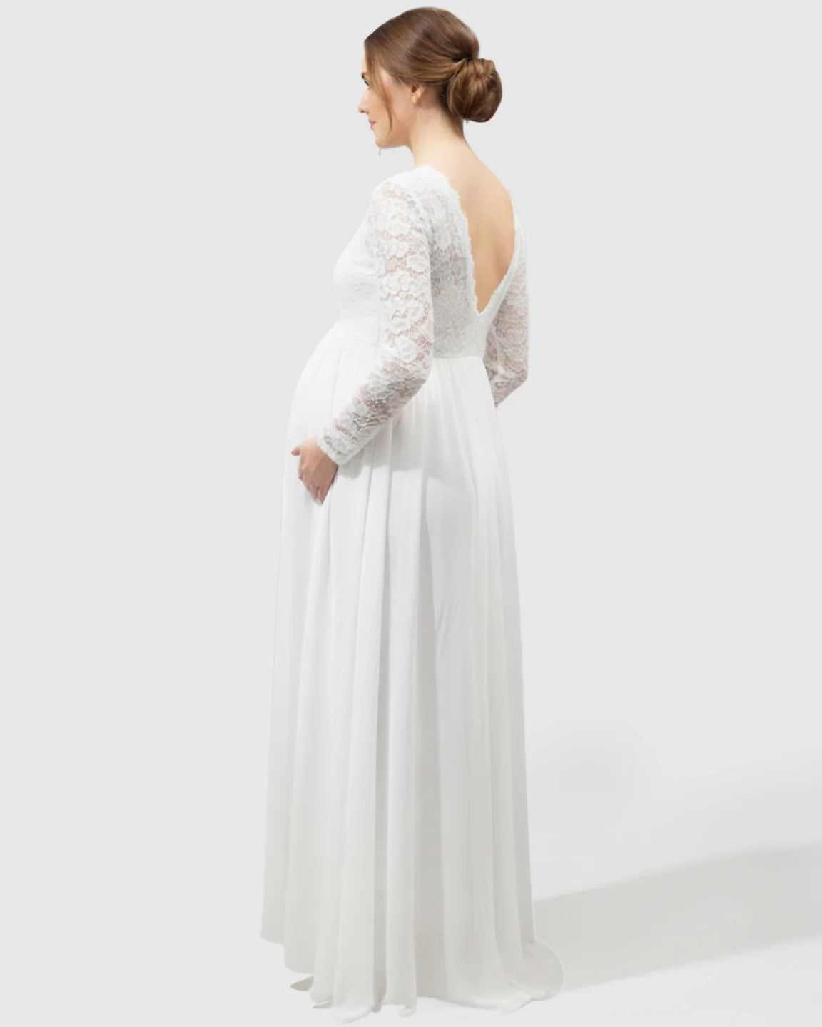 White lace maternity bridal gown with long sleeves, open V-back, empire waist, and flowing skirt.