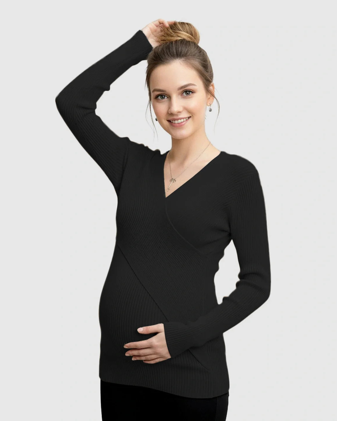 Pregnant woman smiling, wearing a black faux-wrap ribbed maternity top with a V-neck and long sleeves.