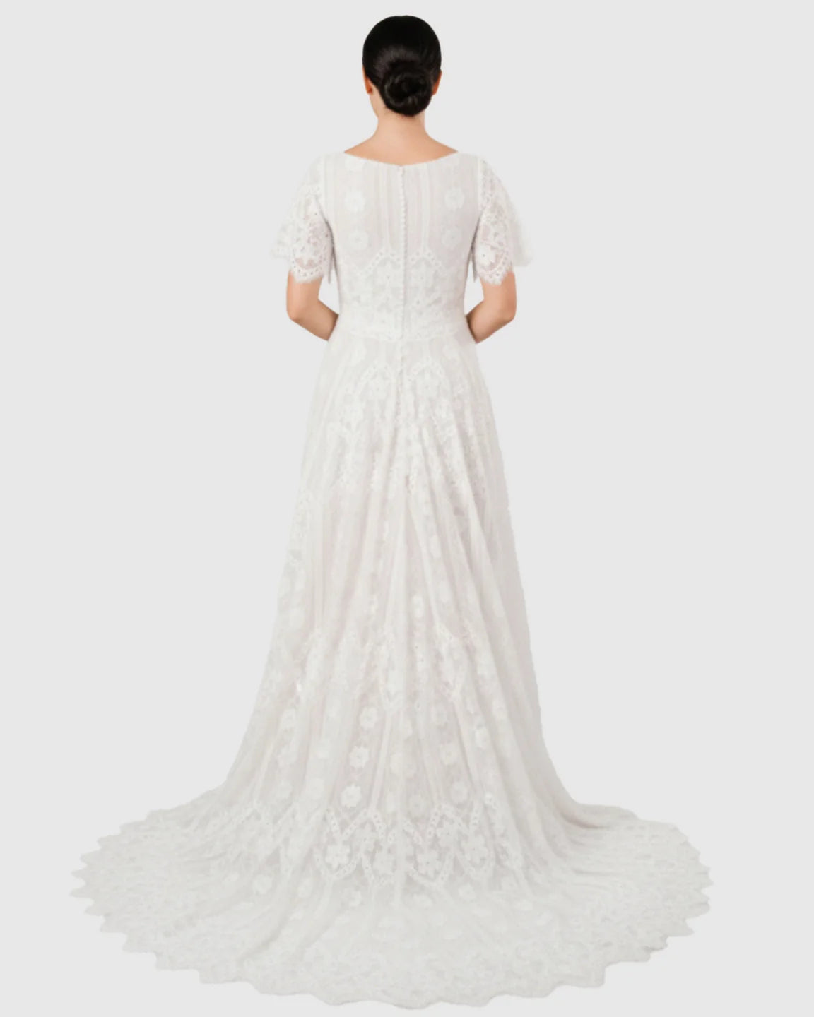 Back view of a white vintage lace flutter-sleeve maternity gown with a long trailing hem.