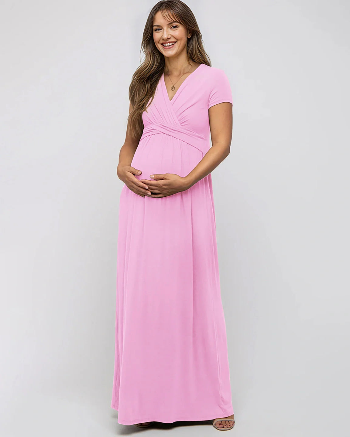 Smiling pregnant woman in a pink Bump Society Twist Front Draped Maternity Nursing Maxi Dress.