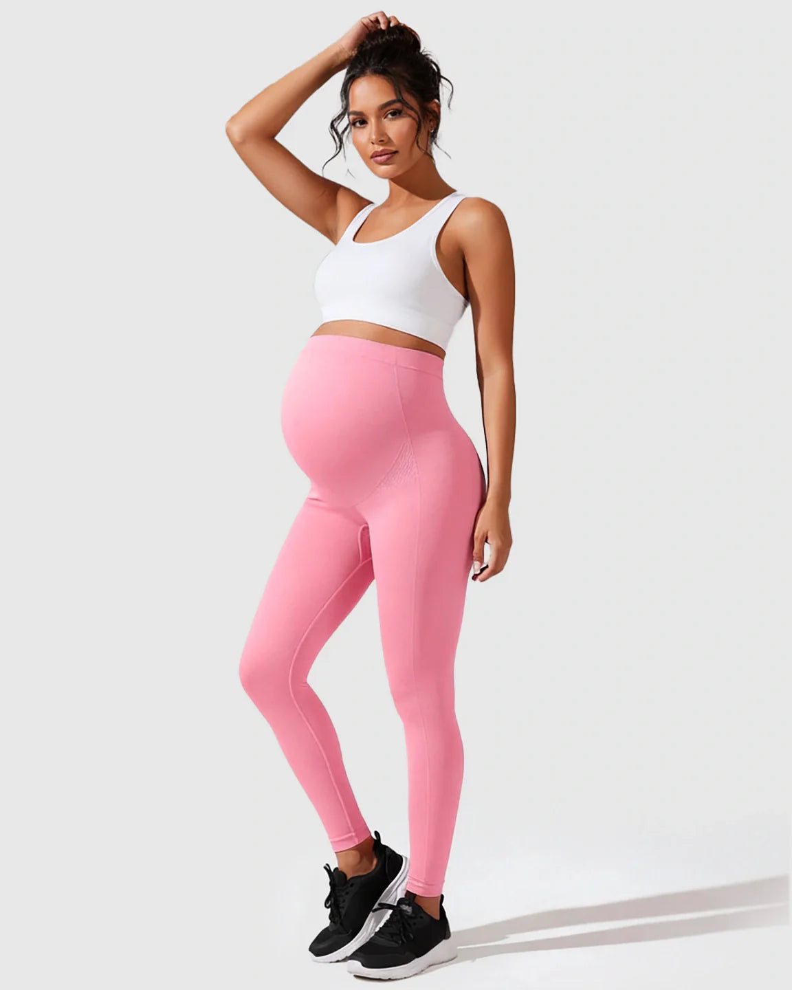 Pregnant woman in pink seamless high-waisted maternity leggings and white sports bra.
