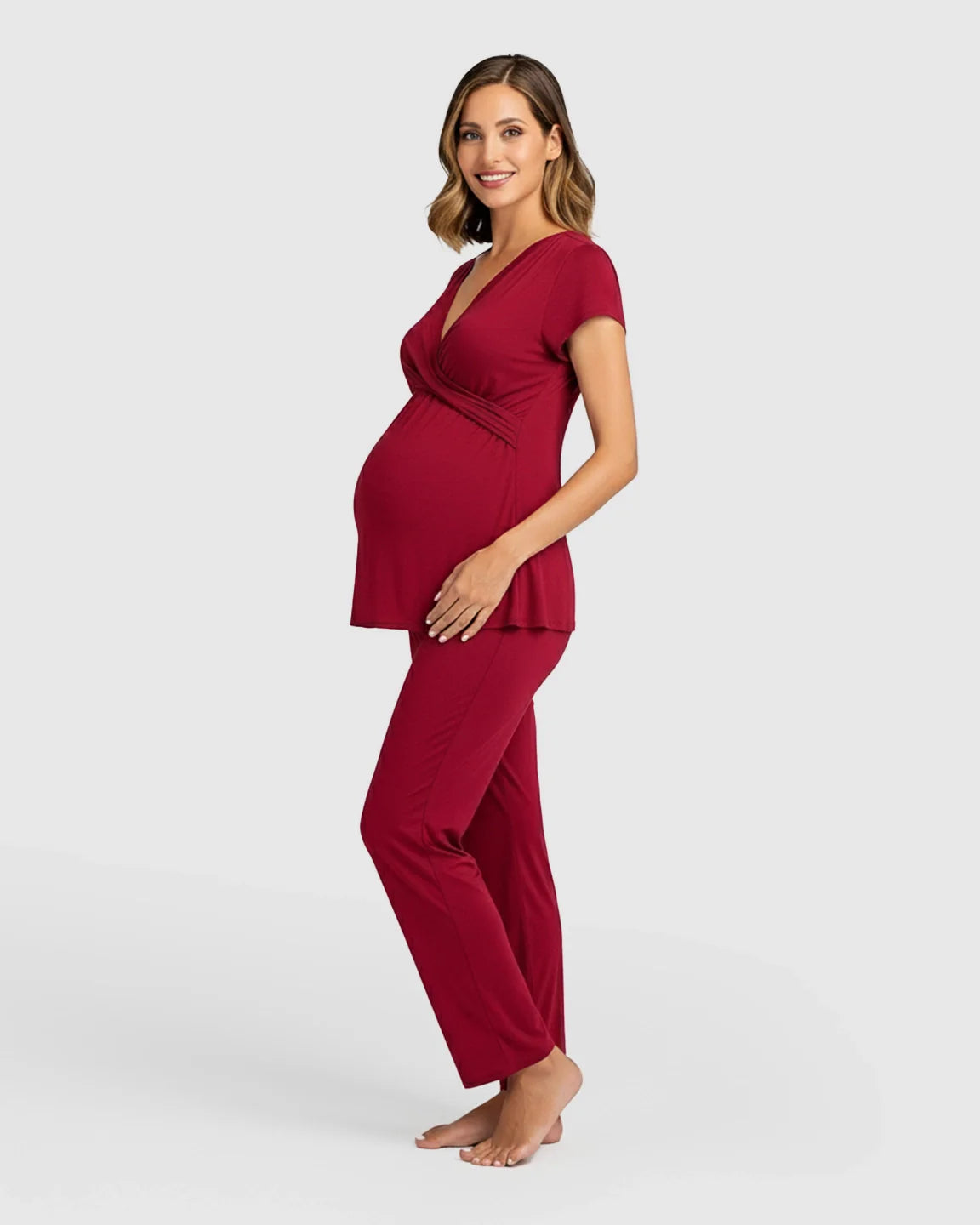Smiling pregnant woman in a red wrap V-neck short-sleeve maternity and nursing sleepwear set.