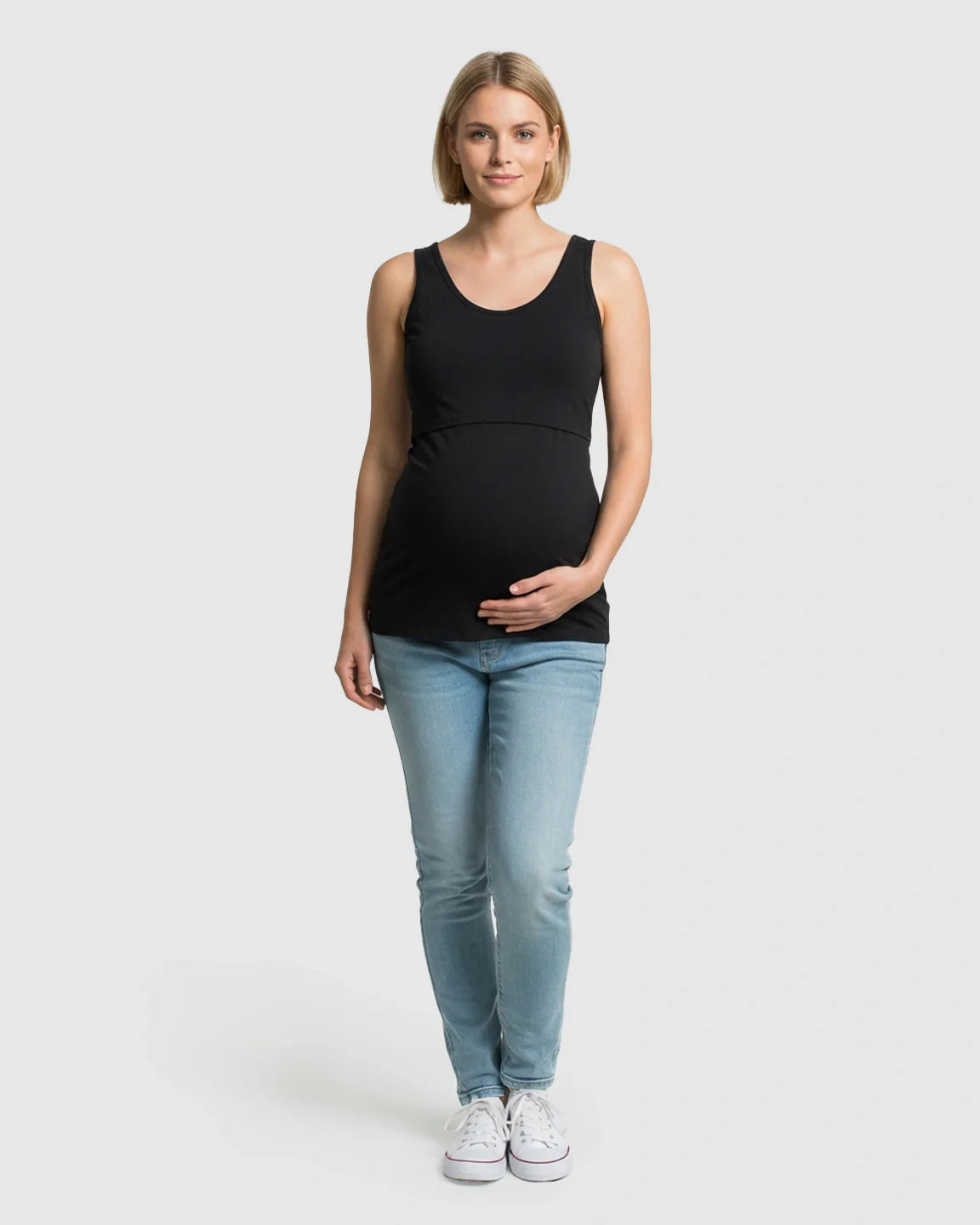 Blonde pregnant woman in a black stretch nursing-access maternity tank top and light wash jeans.