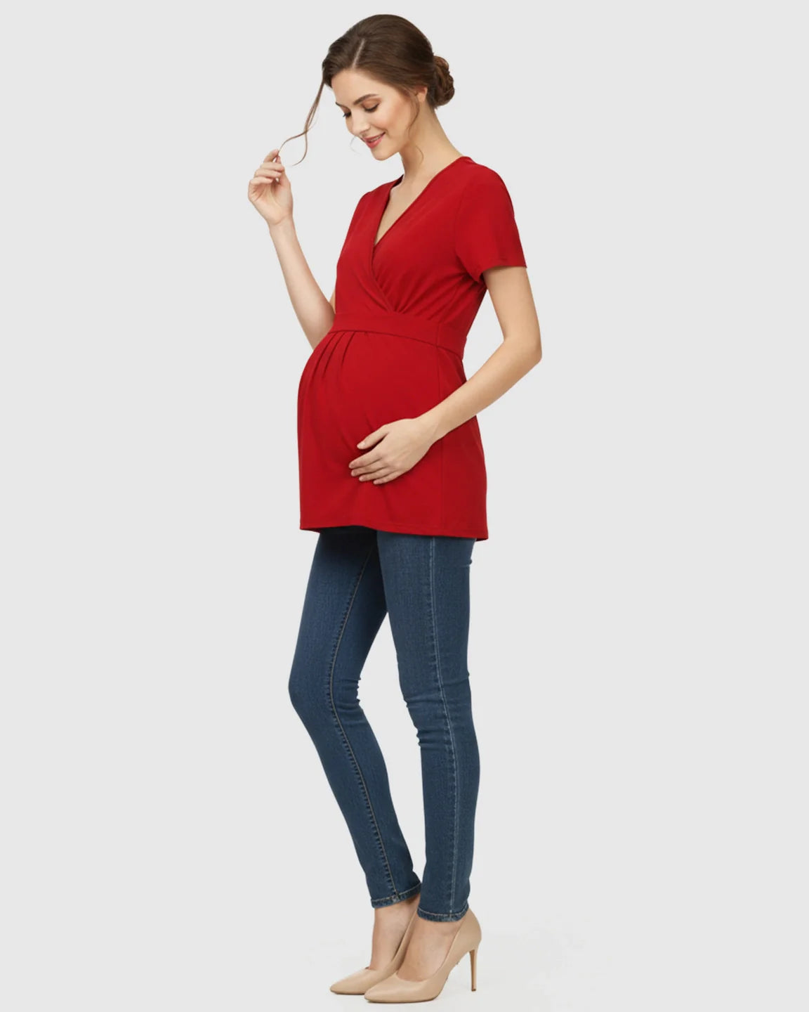 Woman in a red V-neck wrap-style maternity top with an adjustable waist tie, paired with jeans.