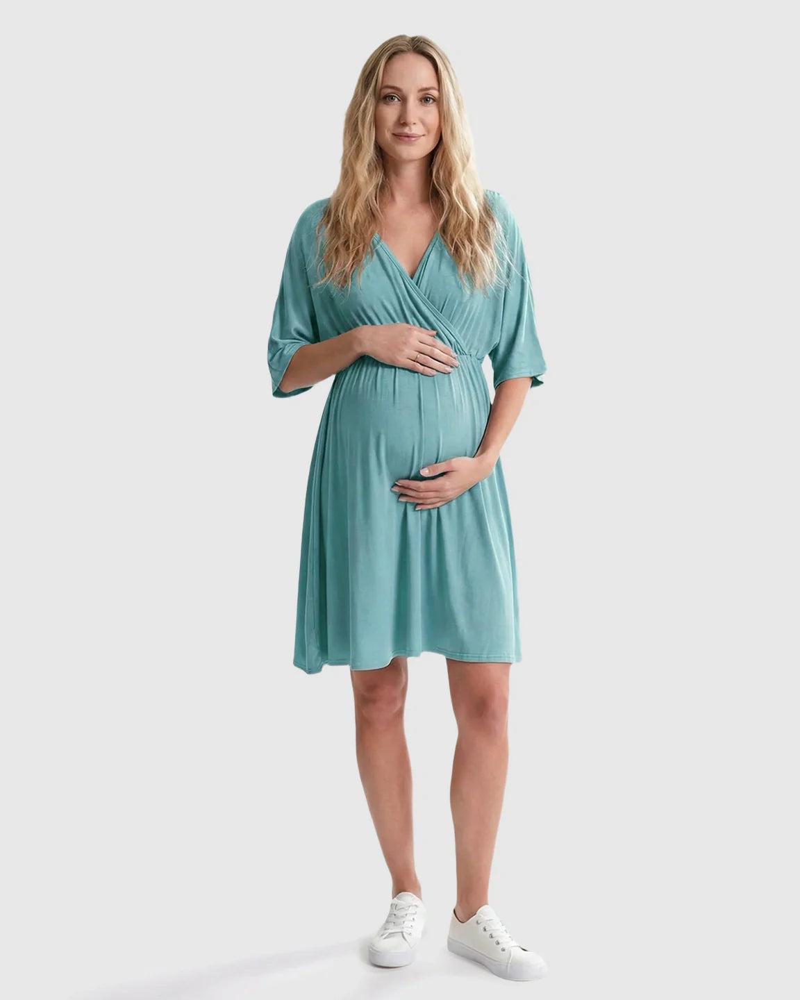 Pregnant woman in a teal cross-front maternity midi dress with 3/4 sleeves, flattering her bump.