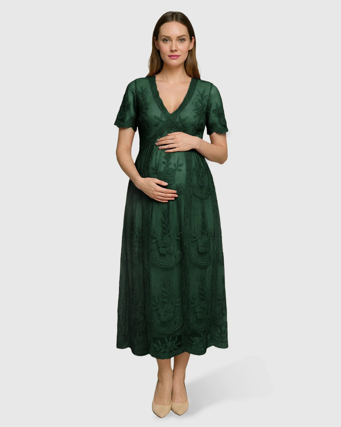 Pregnant woman in a dark green lace maternity midi dress with V-neck, short sleeves, and floral embroidery.