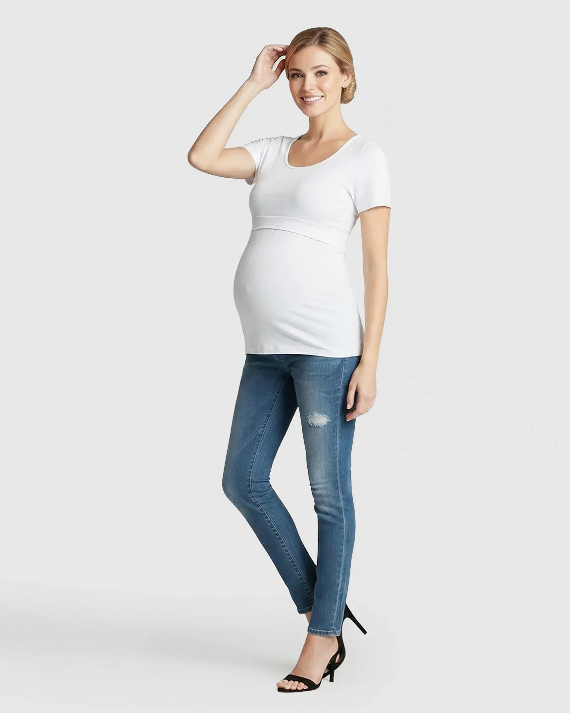 Smiling pregnant woman in a white stretch-fit V-neck nursing t-shirt and jeans.