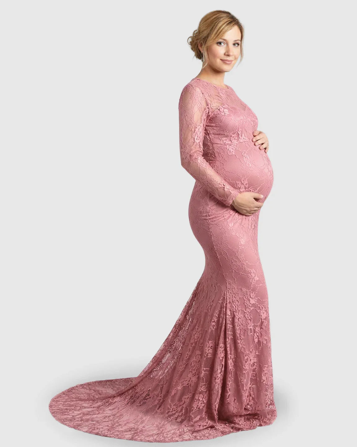 Pregnant woman in a pink sheer lace trumpet maternity gown with long sleeves and a mermaid-style skirt.