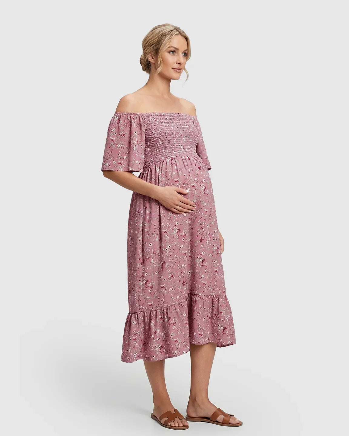 Maternity midi dress in pink floral print with off-shoulder smocked top, flutter sleeves, and tiered skirt.
