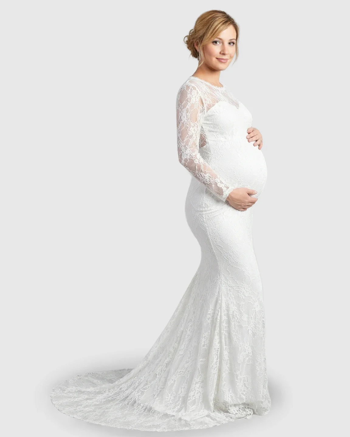 Pregnant woman in a white sheer lace trumpet maternity gown with long sleeves and a mermaid-style skirt.