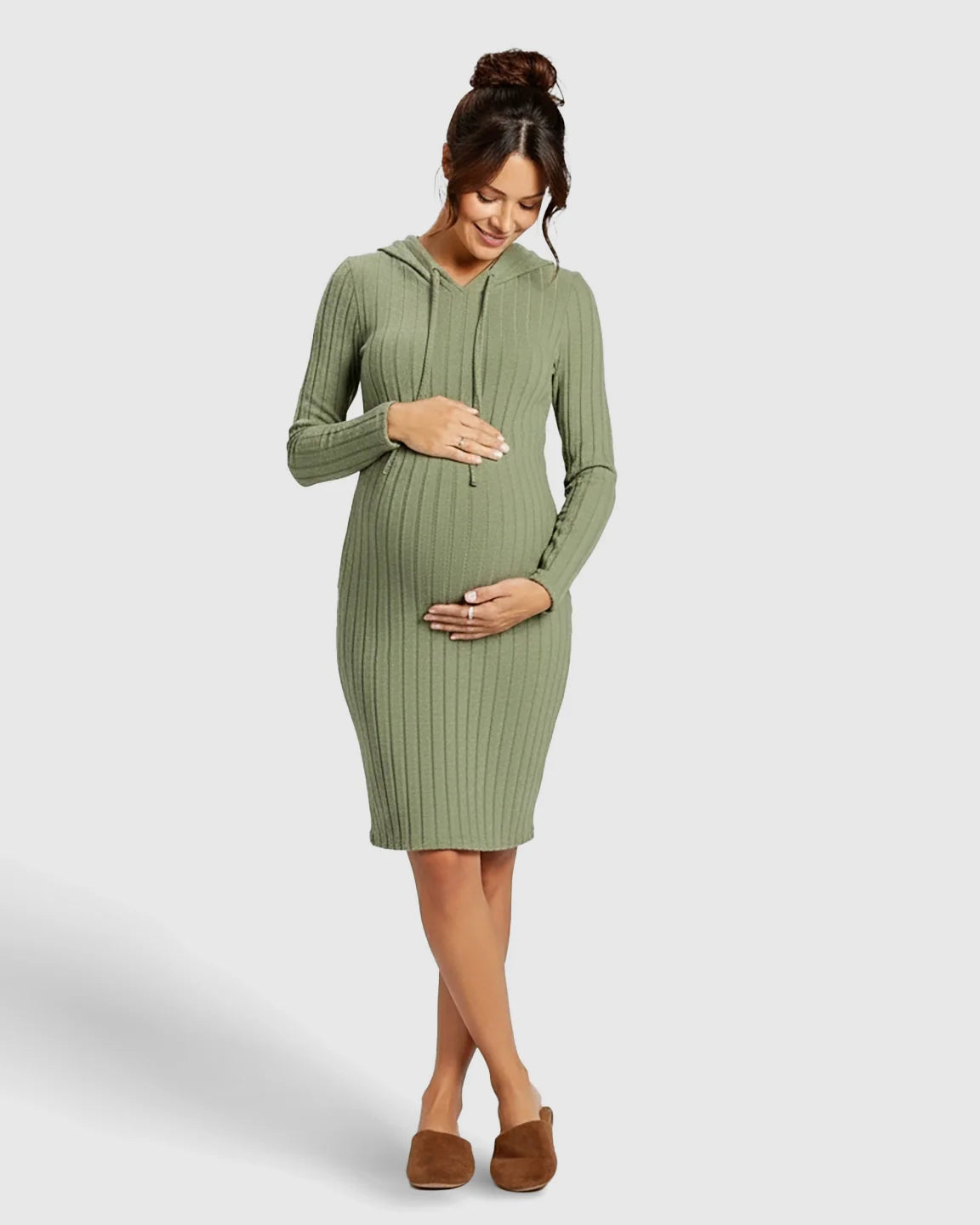 Pregnant woman in a sage green ribbed bodycon hooded maternity midi dress, gently holding her bump.