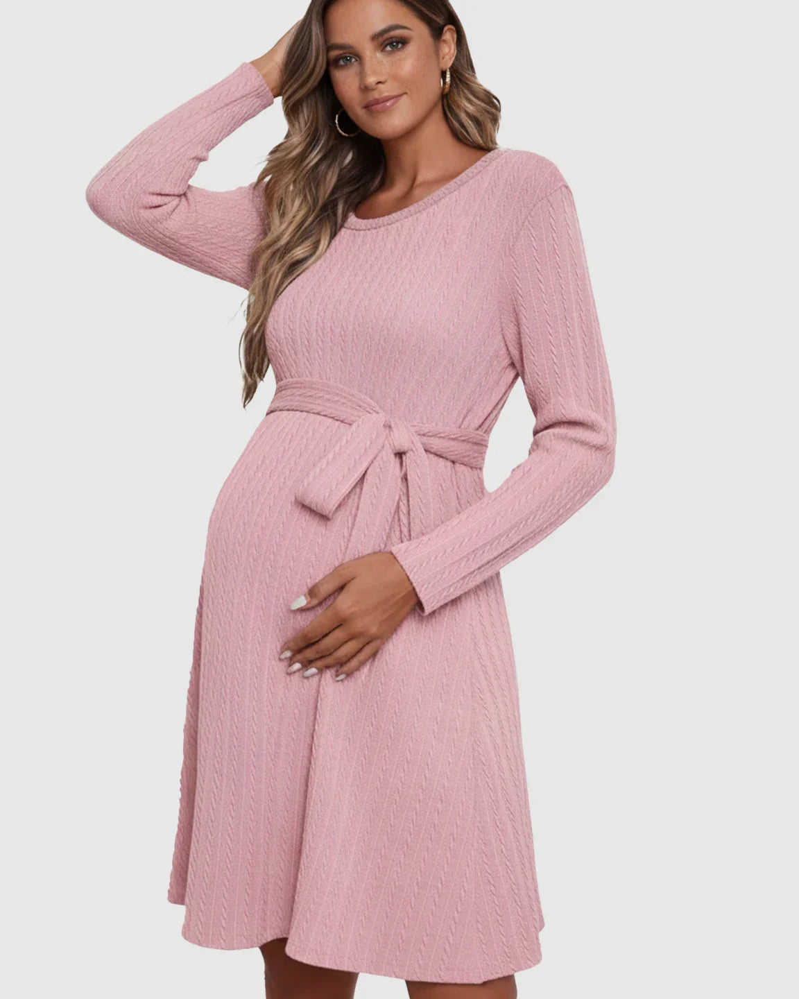 Pregnant woman in a pink ribbed tie-waist maternity midi dress with long sleeves and round neck.