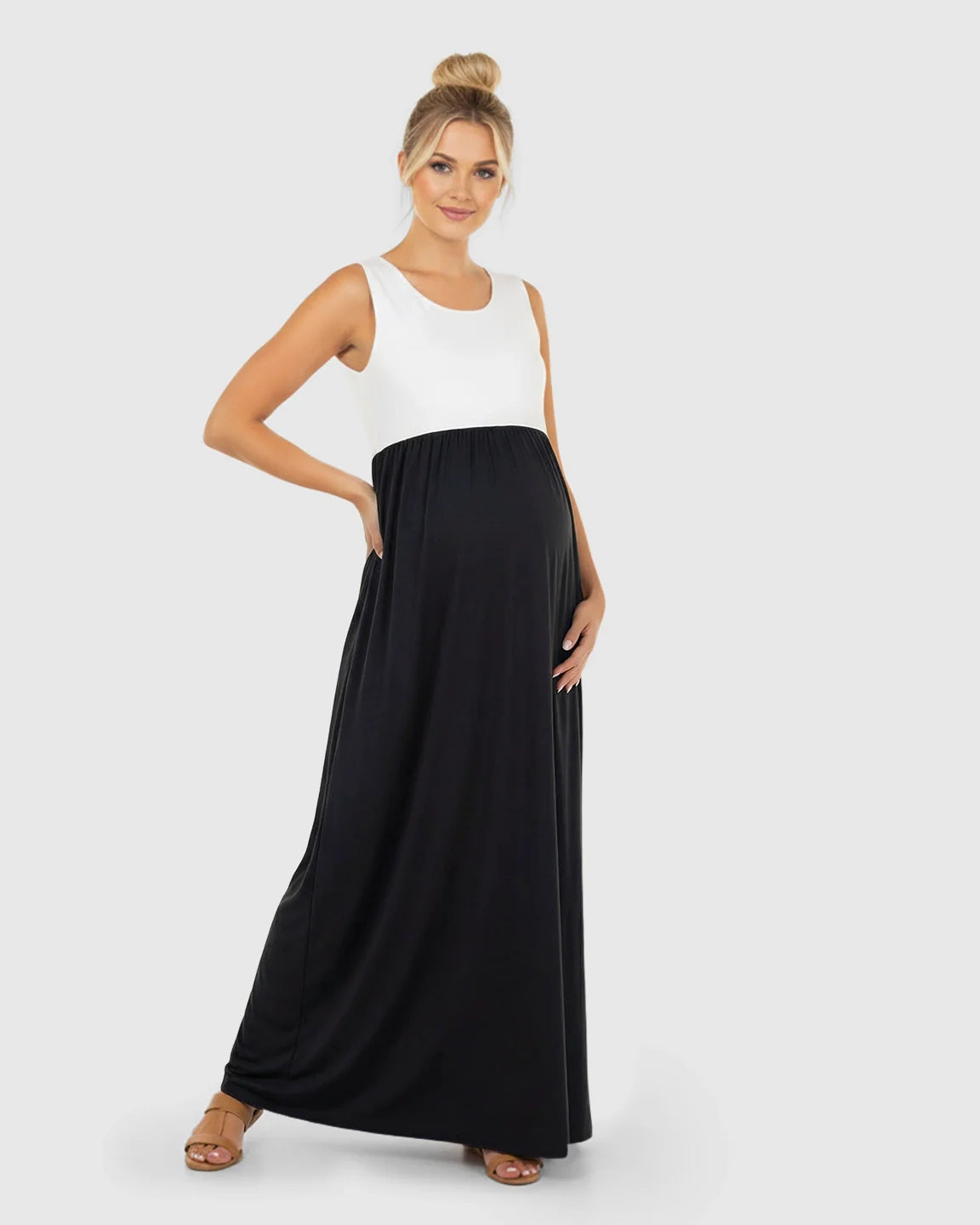 Smiling pregnant woman in a sleeveless, white and black colorblock high-waisted maternity maxi dress.