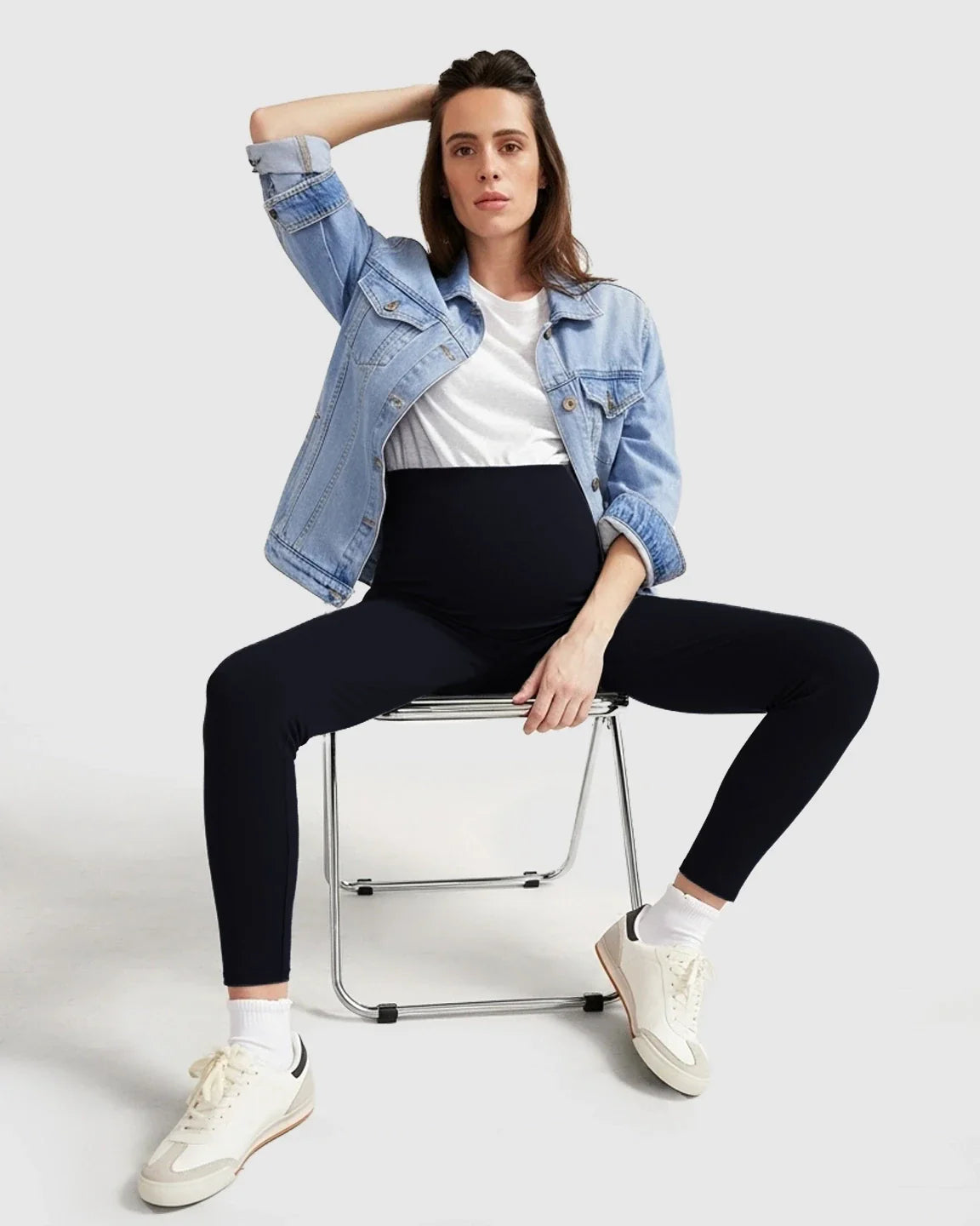 Woman wearing black ultra-soft support maternity midi leggings with a white tee and denim jacket.