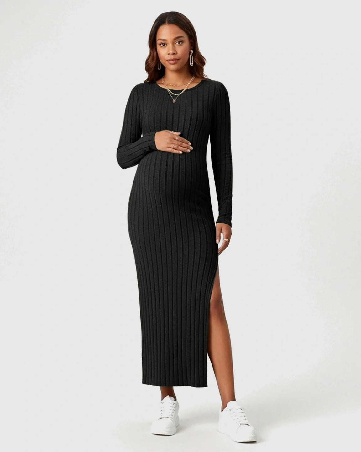 Pregnant woman in a black ribbed knit long-sleeve maternity maxi dress with a high side slit.