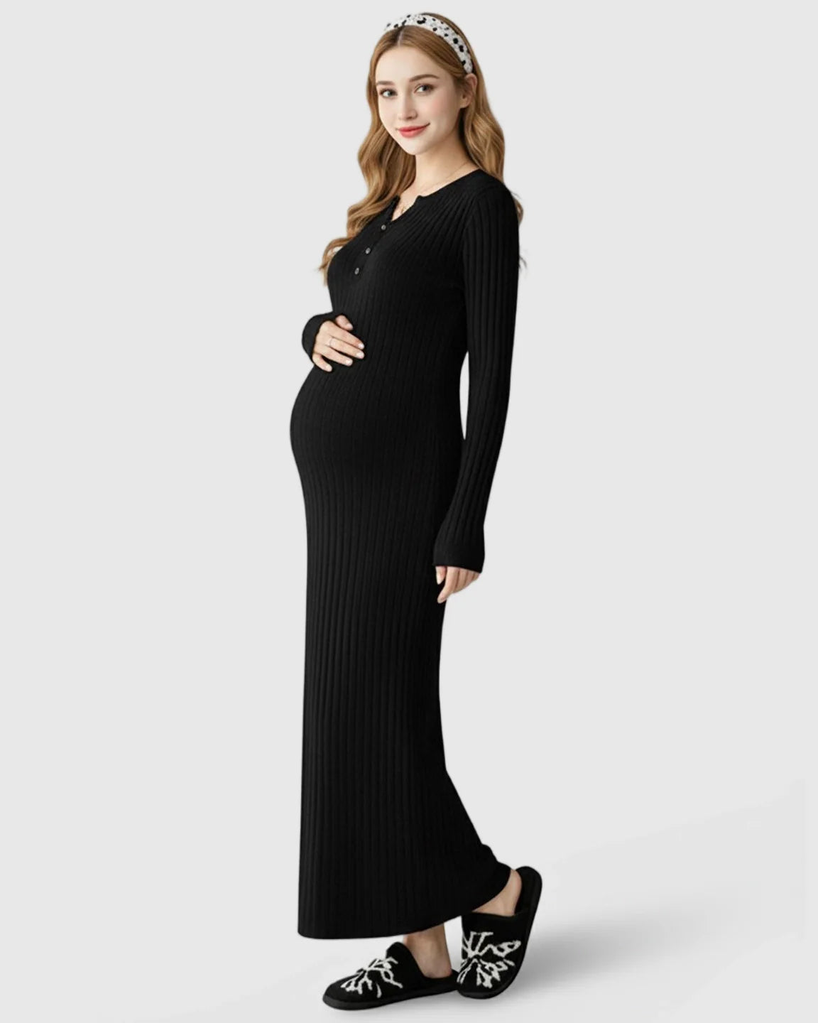 Pregnant woman in a black ribbed knit A-line long sleeve maternity maxi dress, holding her bump.