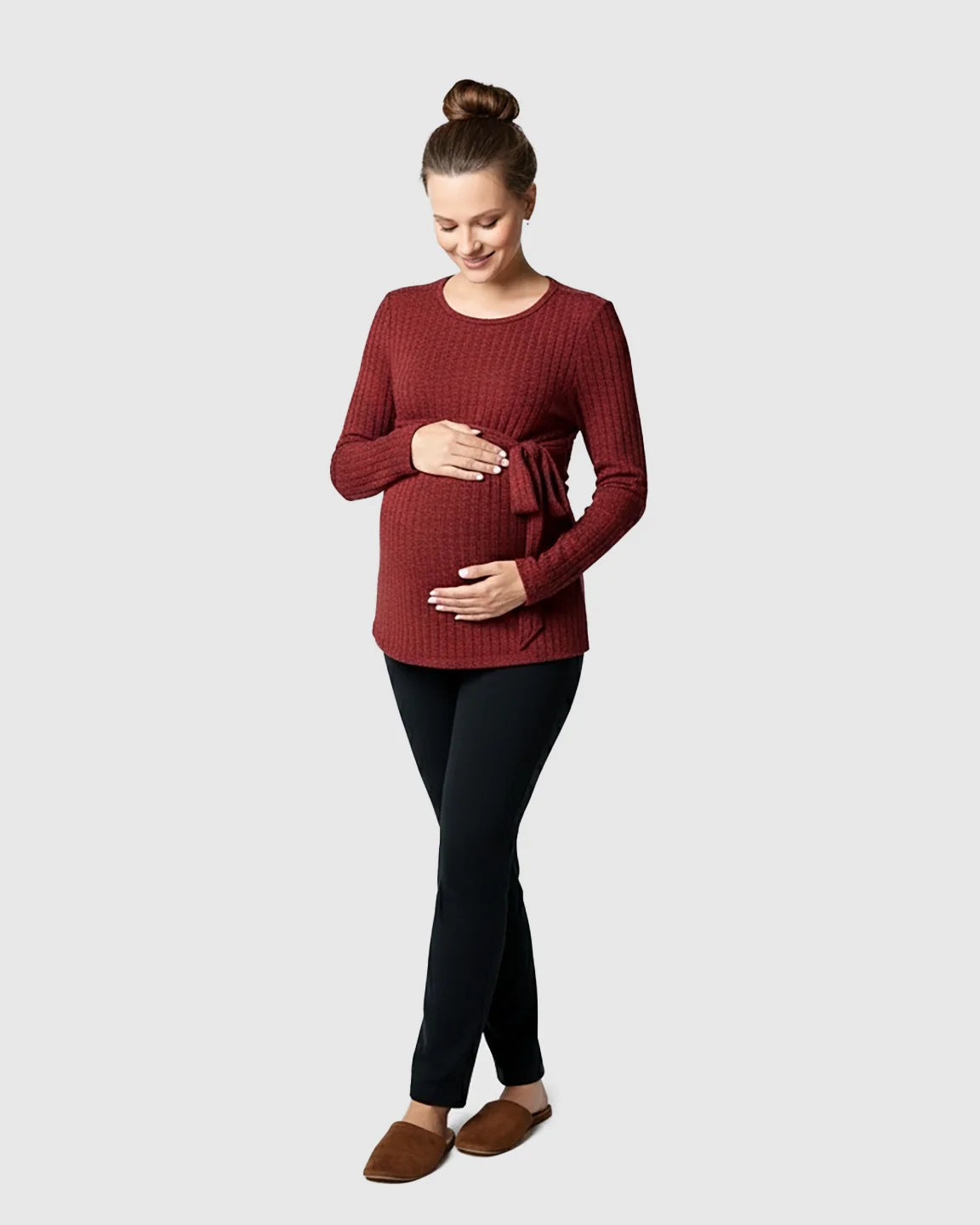 Pregnant woman in a red ribbed tie-waist long sleeve maternity sweater and black pants.