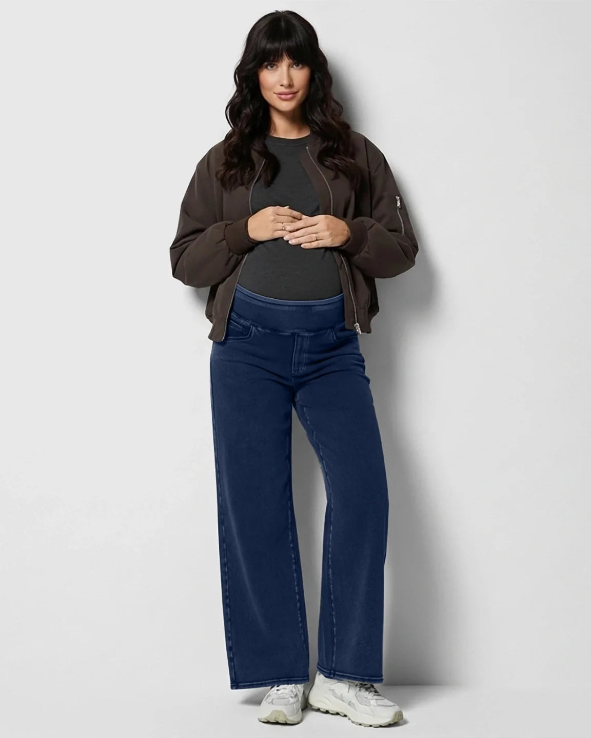 Maternity model in dark wash wide-leg denim jeans with a soft waistband, gray tee, and brown bomber jacket.