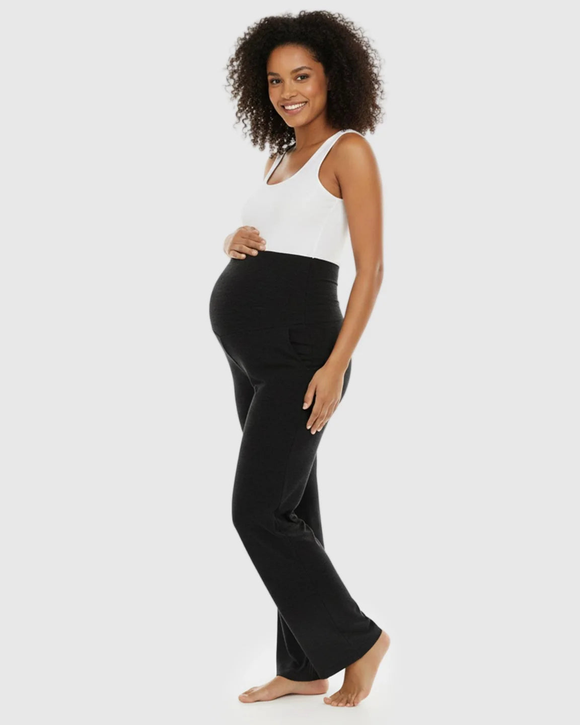 Smiling pregnant woman in black wide-leg maternity lounge pants with a foldable waistband and side pockets.