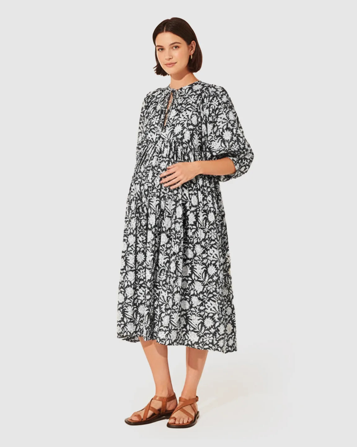 Pregnant woman in a black and white floral loose-fit maternity midi dress with gathered shoulders and puff sleeves.