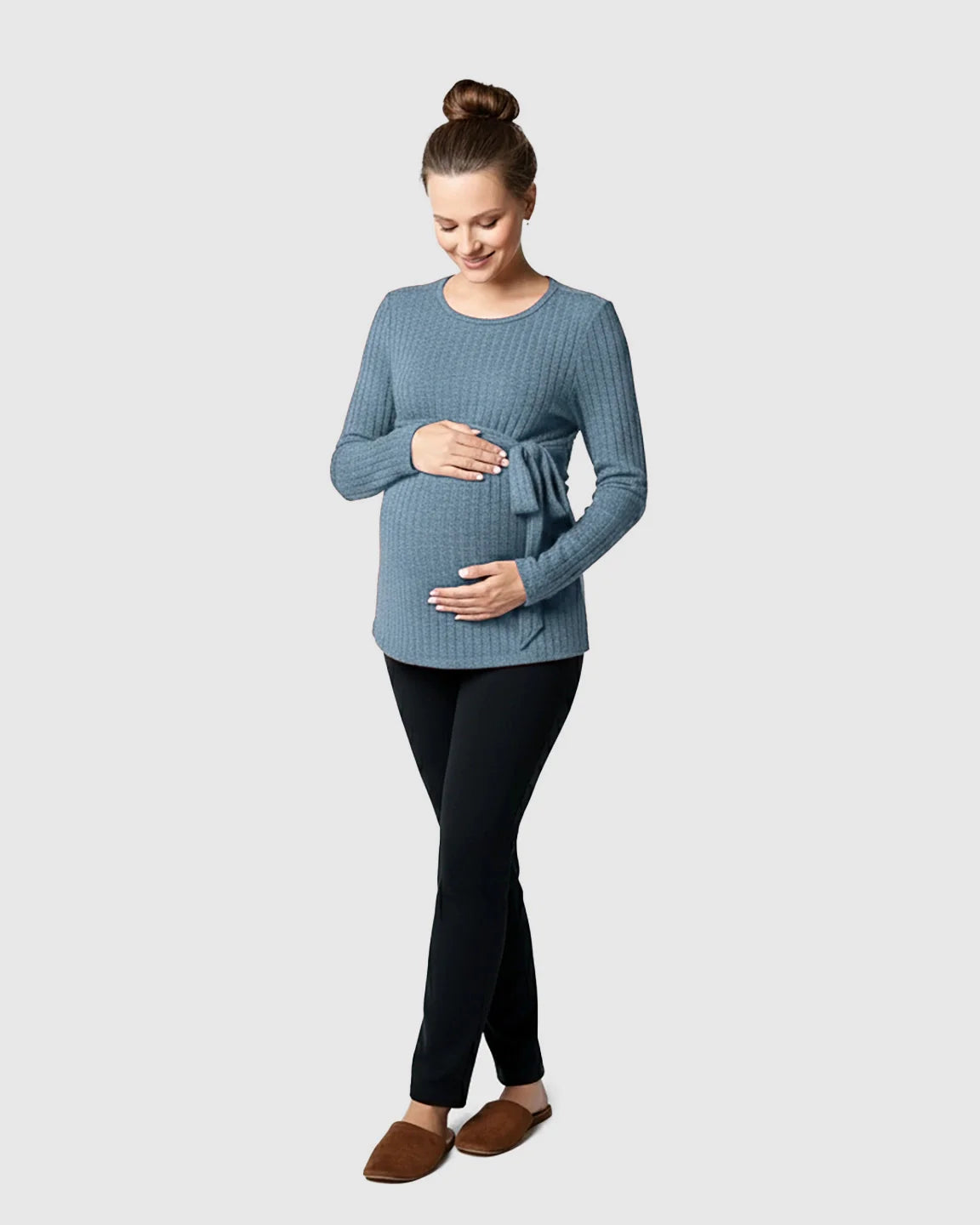Pregnant woman in a blue ribbed tie-waist long sleeve maternity sweater and black pants.