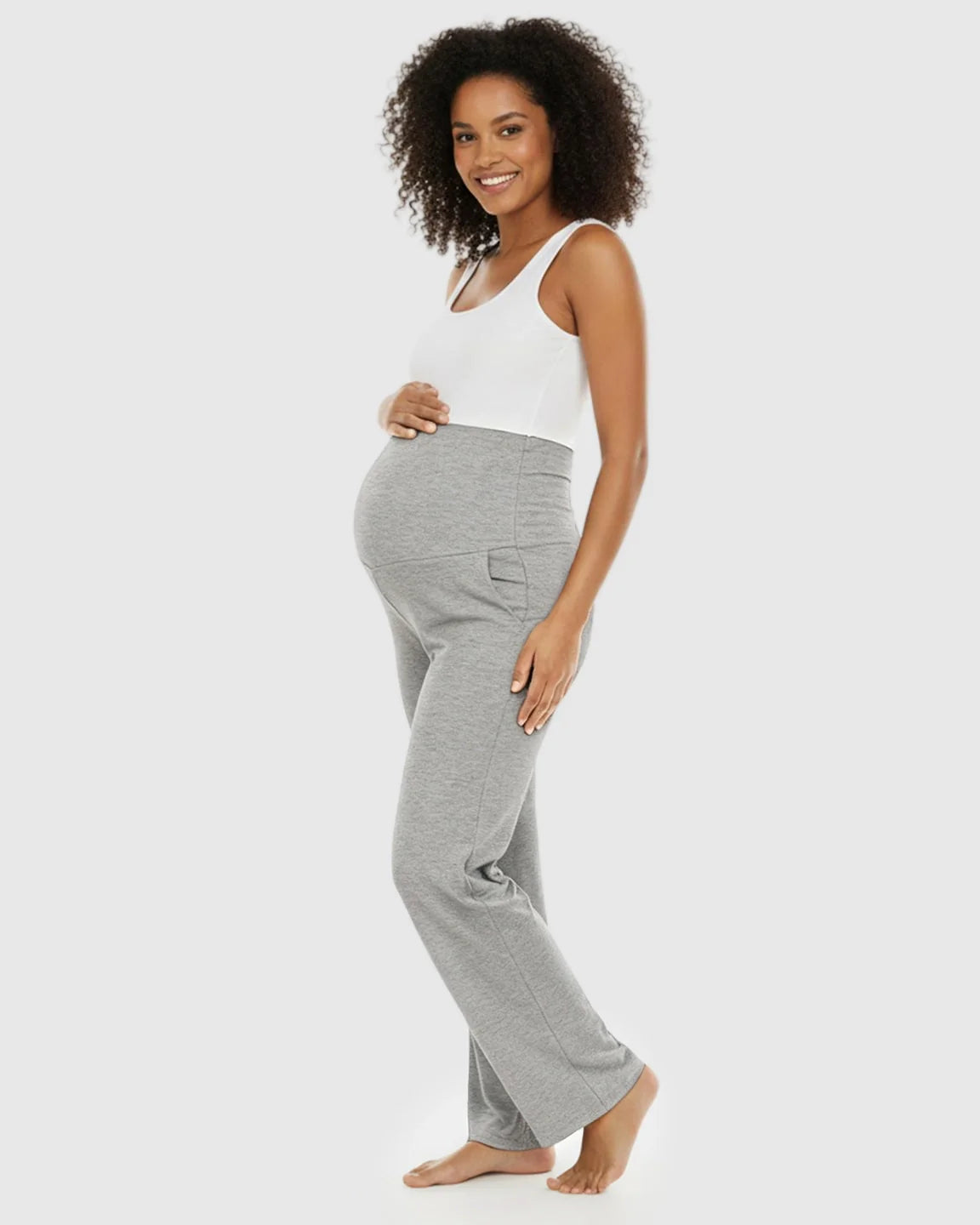 Smiling pregnant woman in gray wide-leg maternity lounge pants with a foldable waistband and side pockets.